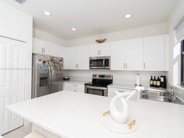 kitchen featuring appliances with stainless steel finishes, kitchen peninsula, sink, and white cabinets