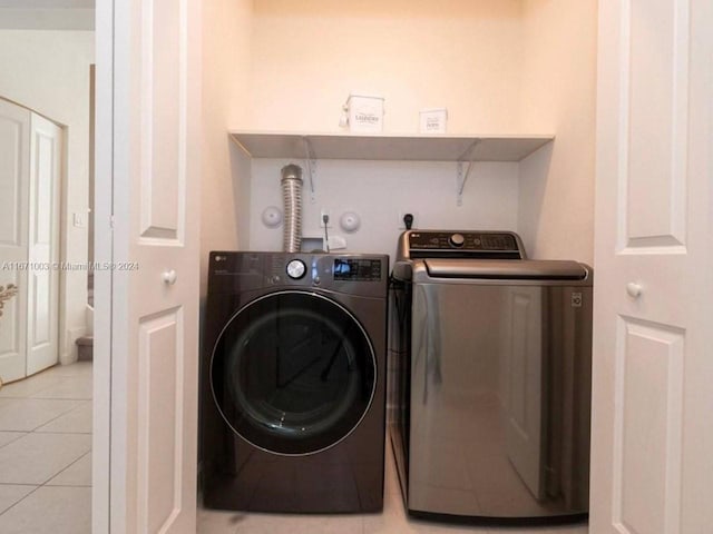 clothes washing area featuring washer and clothes dryer and light tile patterned floors