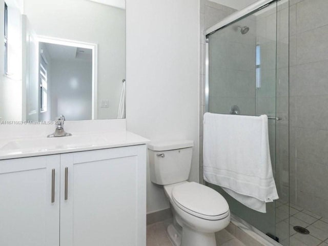 bathroom with tile patterned flooring, vanity, toilet, and a shower with shower door