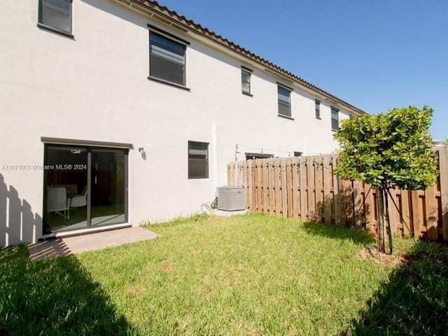 rear view of property featuring a lawn and central air condition unit