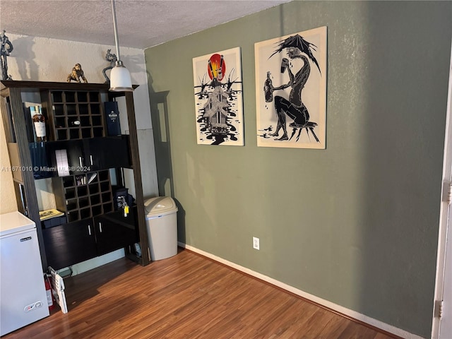 interior space with a textured ceiling and hardwood / wood-style flooring