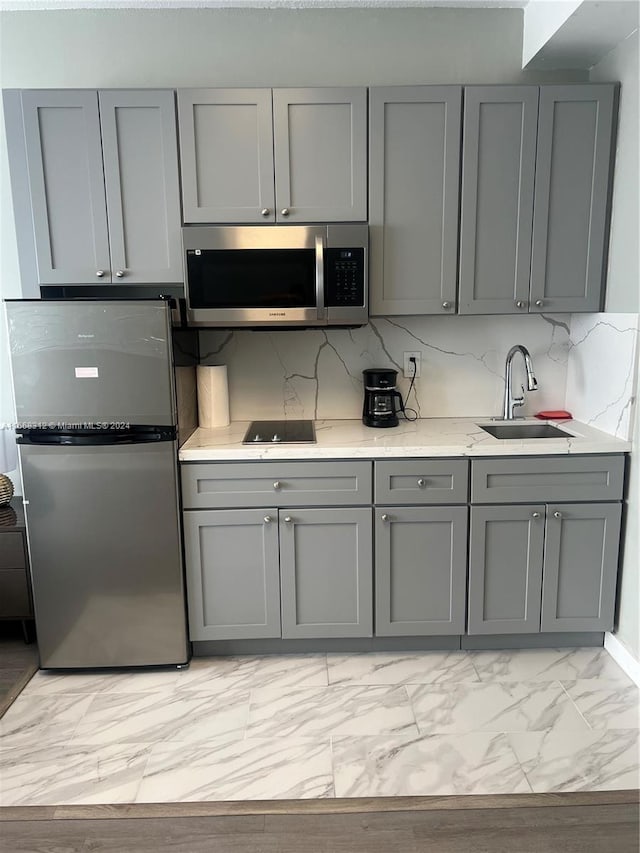 kitchen featuring gray cabinets, stainless steel appliances, tasteful backsplash, and sink