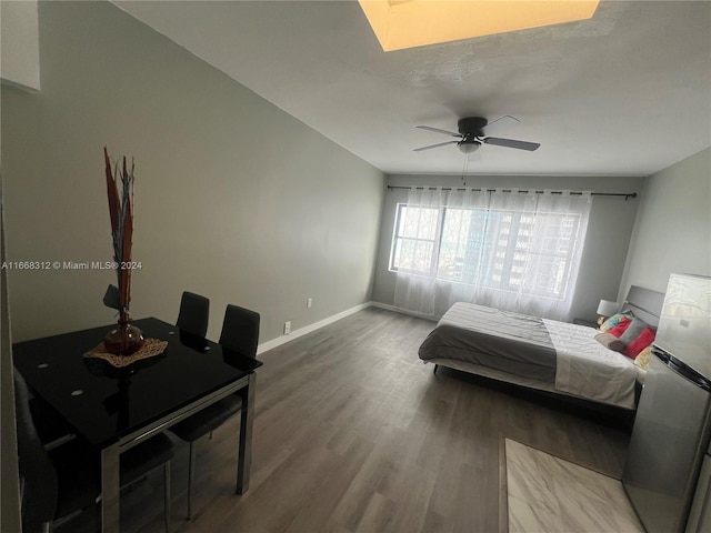 bedroom with ceiling fan, stainless steel fridge, and hardwood / wood-style floors