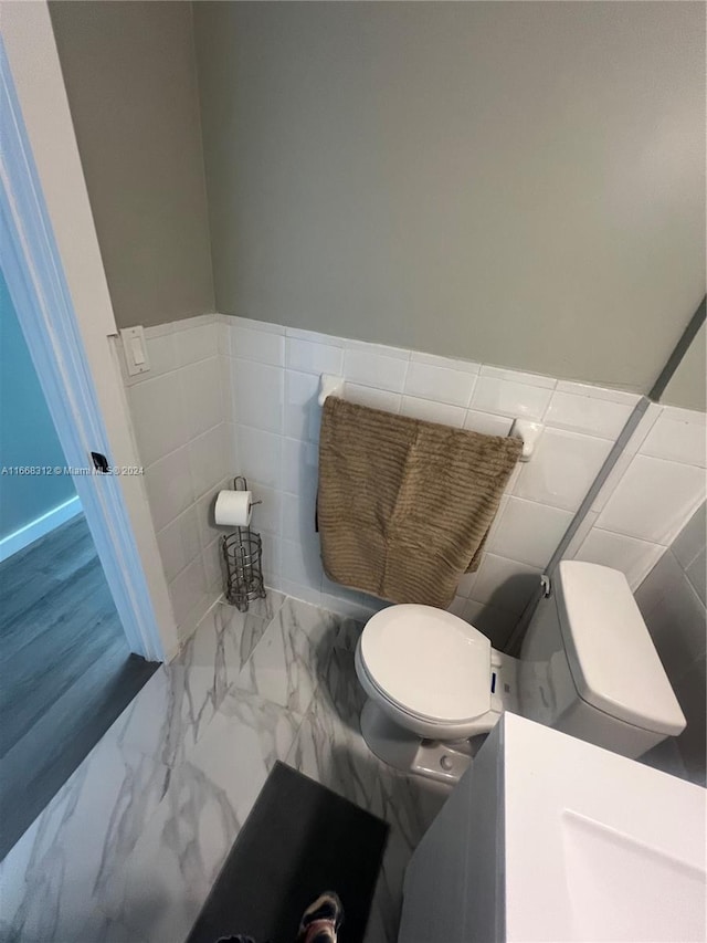 bathroom featuring tile walls, toilet, and hardwood / wood-style flooring