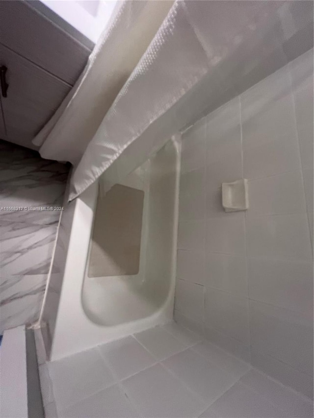 bathroom with curtained shower and tile patterned floors