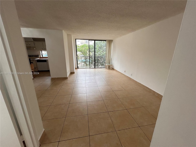 spare room with a wall of windows, a textured ceiling, and light tile patterned floors