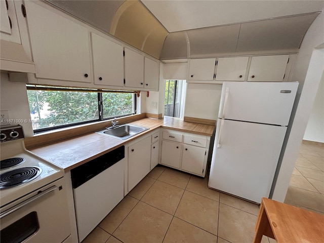 kitchen with white appliances, sink, light tile patterned floors, and white cabinets