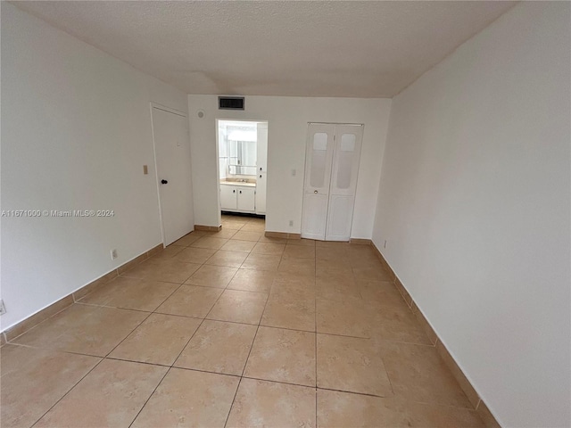 tiled empty room featuring a textured ceiling