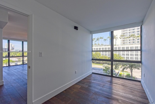 empty room with dark wood-type flooring, a healthy amount of sunlight, and expansive windows