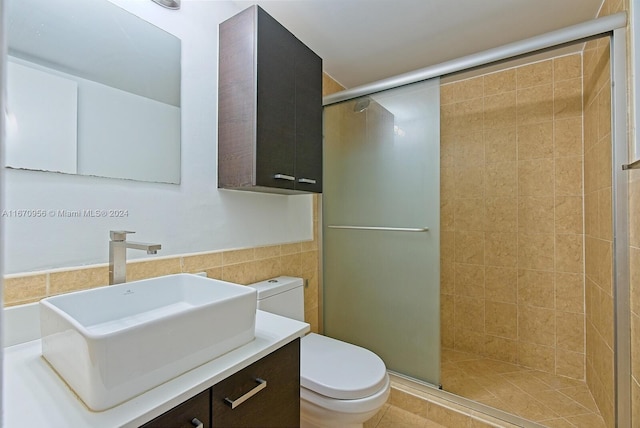 bathroom featuring tile walls, tile patterned flooring, a shower with shower door, vanity, and toilet