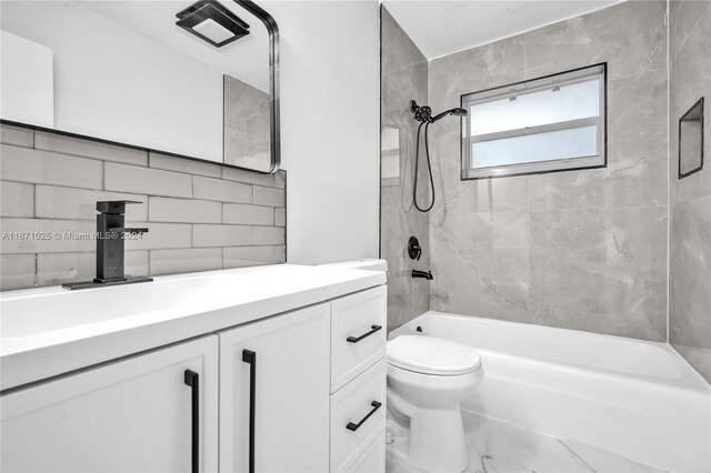 full bathroom featuring decorative backsplash, tiled shower / bath, vanity, and toilet