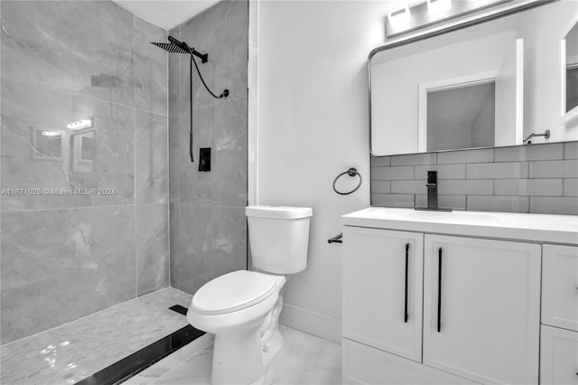 bathroom featuring vanity, tiled shower, toilet, and decorative backsplash