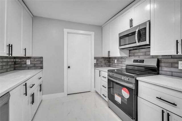 kitchen with light stone counters, stainless steel appliances, backsplash, and white cabinetry