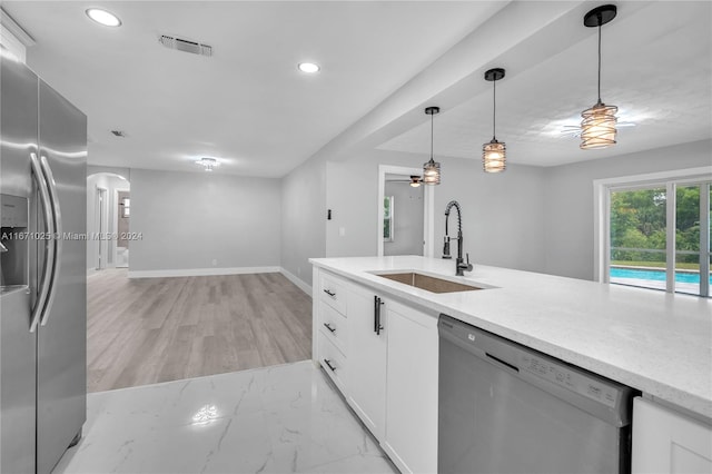 kitchen with pendant lighting, white cabinets, appliances with stainless steel finishes, and sink