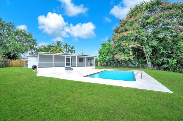 rear view of house with a sunroom, a patio, a fenced in pool, and a lawn