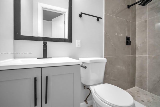 bathroom with tiled shower, vanity, and toilet