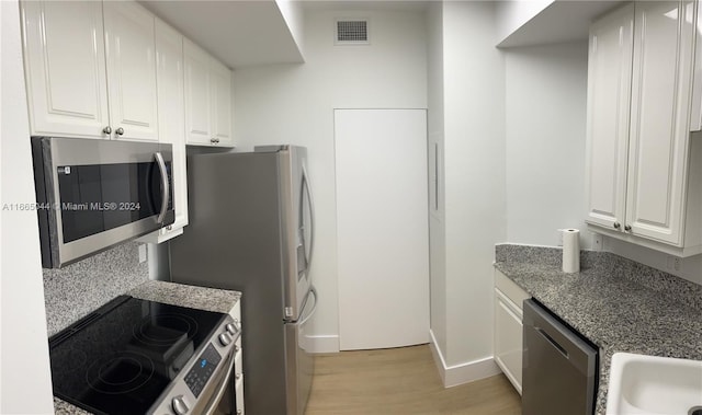 kitchen with appliances with stainless steel finishes, light wood-type flooring, sink, and white cabinets