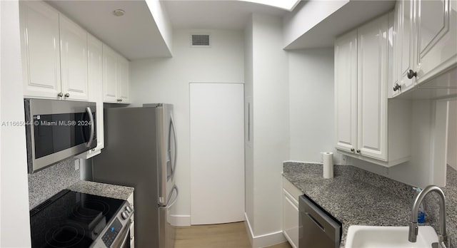 kitchen featuring white cabinets, sink, light hardwood / wood-style flooring, appliances with stainless steel finishes, and decorative backsplash