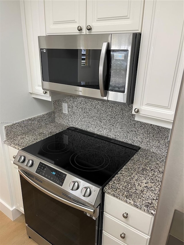 kitchen with white cabinetry, stone countertops, and stainless steel appliances