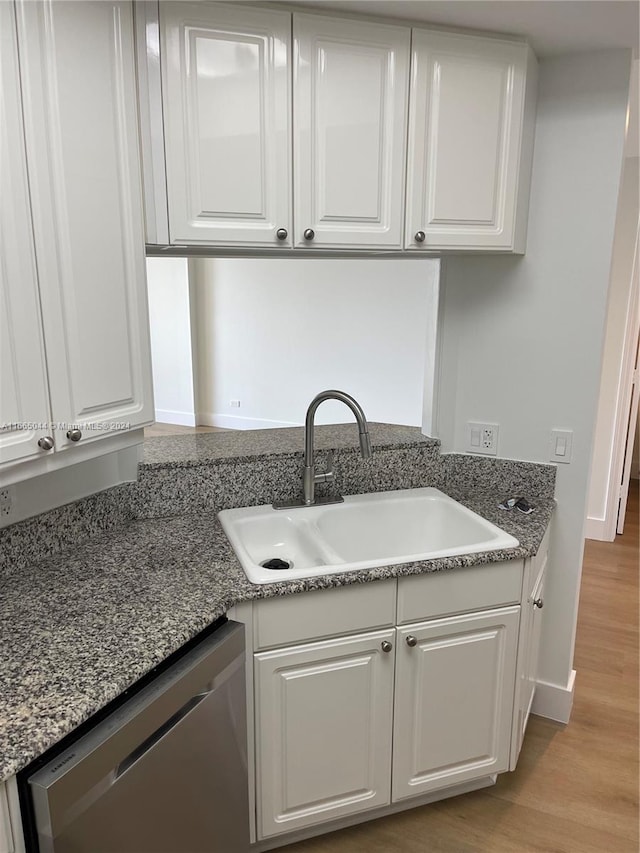 kitchen featuring light hardwood / wood-style flooring, stainless steel dishwasher, sink, and white cabinetry