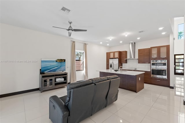 kitchen with a kitchen island with sink, appliances with stainless steel finishes, plenty of natural light, and wall chimney range hood