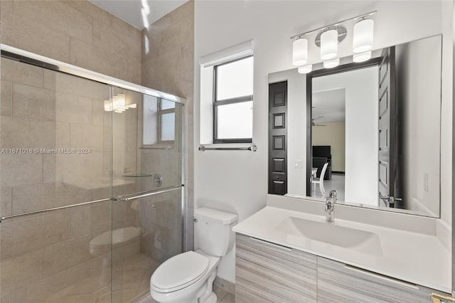 bathroom featuring ceiling fan, a shower with shower door, vanity, and toilet