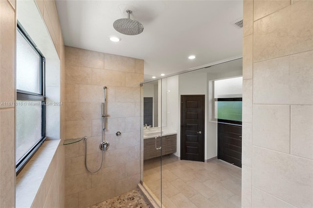 bathroom with vanity, plenty of natural light, and tiled shower