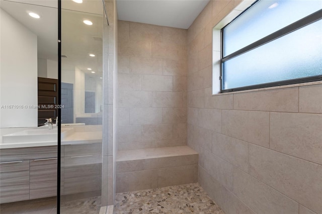 bathroom featuring a tile shower and vanity