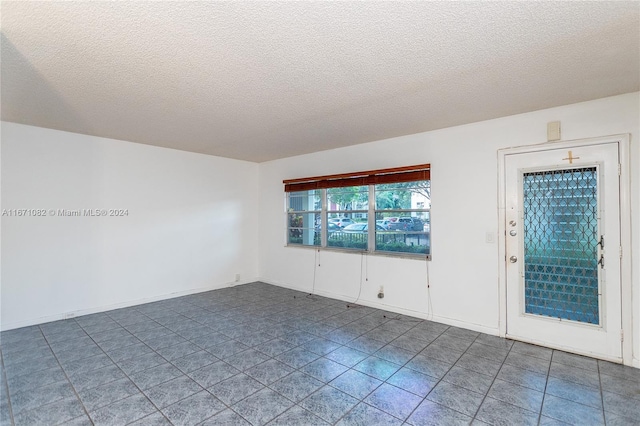 tiled spare room with a textured ceiling