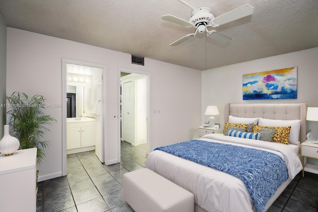 bedroom with tile patterned flooring, ceiling fan, a textured ceiling, and ensuite bath