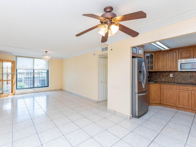 kitchen featuring light tile patterned flooring, stainless steel appliances, dark stone countertops, ceiling fan with notable chandelier, and crown molding