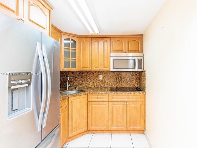 kitchen featuring light tile patterned flooring, sink, appliances with stainless steel finishes, dark stone countertops, and decorative backsplash