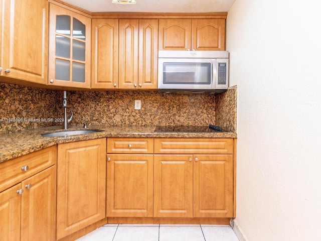 kitchen with dark stone counters, sink, decorative backsplash, light tile patterned floors, and black electric cooktop