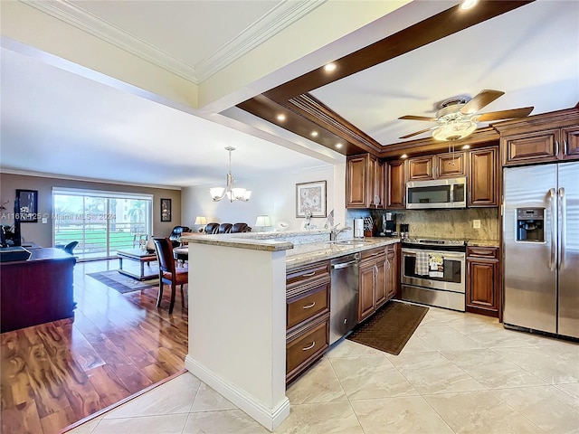 kitchen with a peninsula, open floor plan, appliances with stainless steel finishes, and crown molding