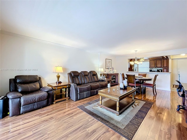 living area with light wood-type flooring, ornamental molding, and an inviting chandelier