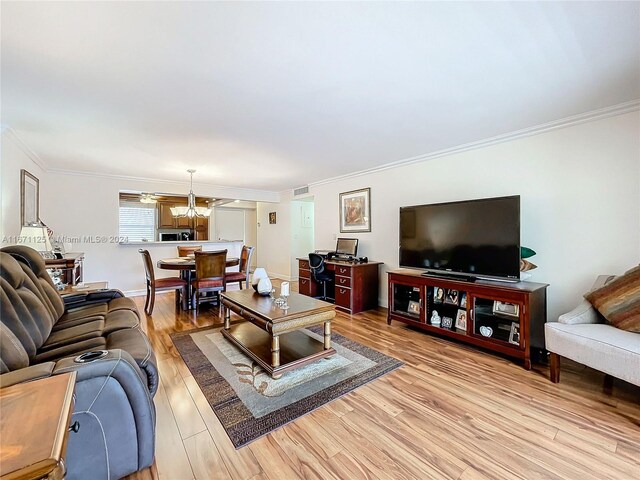 living room with light hardwood / wood-style flooring, an inviting chandelier, and crown molding