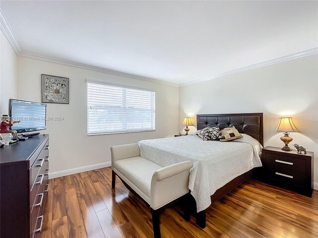 bedroom with ornamental molding and dark hardwood / wood-style floors