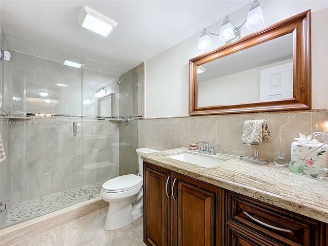 bathroom featuring tile walls, vanity, a shower with door, toilet, and tile patterned floors