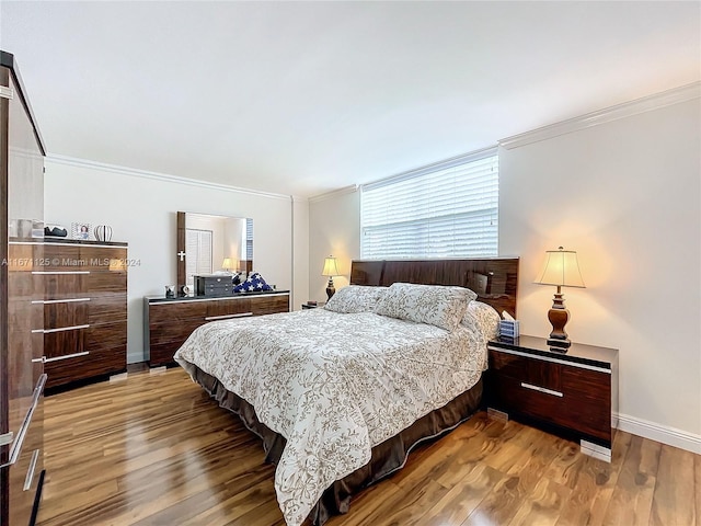 bedroom with baseboards, ornamental molding, and wood finished floors