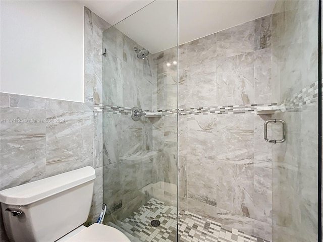 full bath with a shower stall, toilet, and tile walls
