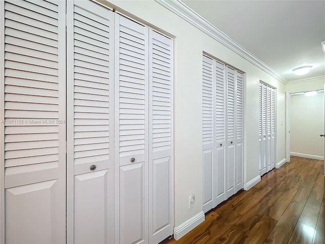 corridor with dark wood-style flooring, ornamental molding, and baseboards