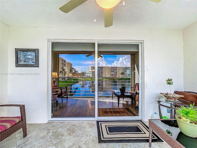 doorway to outside with tile patterned floors, a ceiling fan, and a textured ceiling