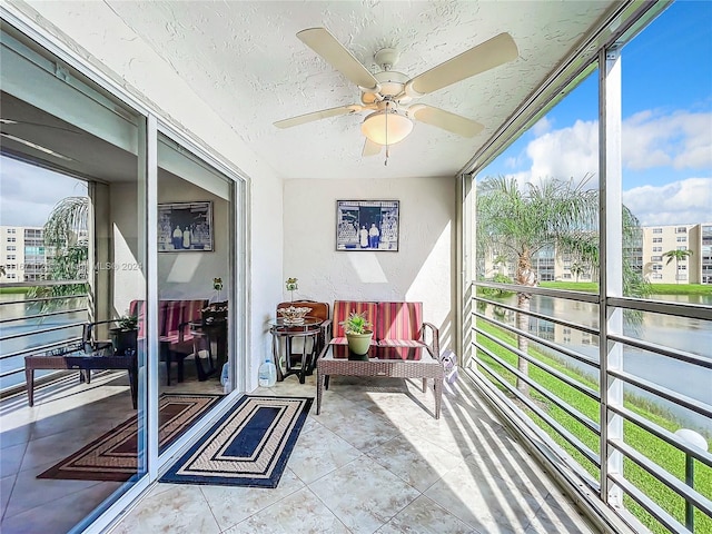 sunroom / solarium featuring ceiling fan and a water view