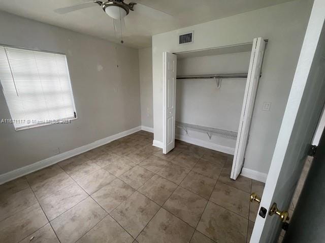 unfurnished bedroom with ceiling fan and a closet