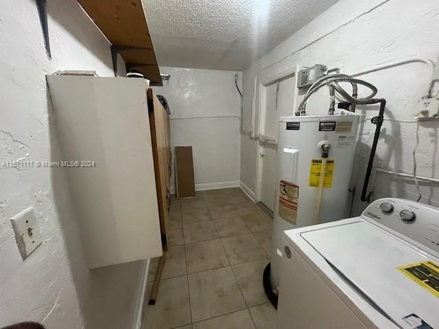 washroom with light tile patterned floors, a textured ceiling, water heater, and washer / dryer