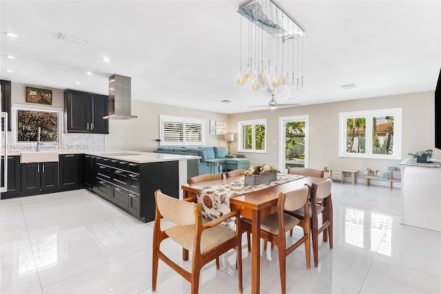 dining area with sink, light tile patterned floors, and ceiling fan with notable chandelier