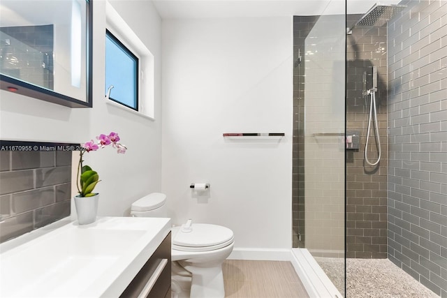 bathroom featuring vanity, toilet, and a tile shower