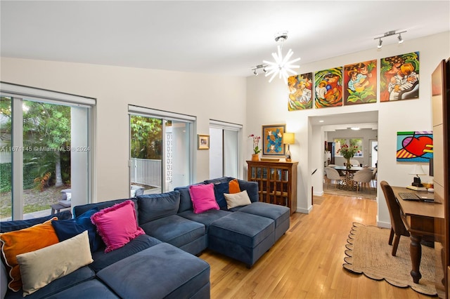 living room with light hardwood / wood-style flooring, vaulted ceiling, a notable chandelier, and track lighting