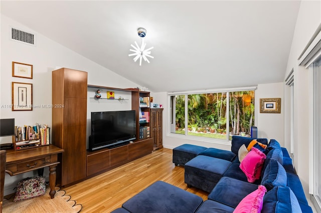 living room with a notable chandelier, light wood-type flooring, and lofted ceiling