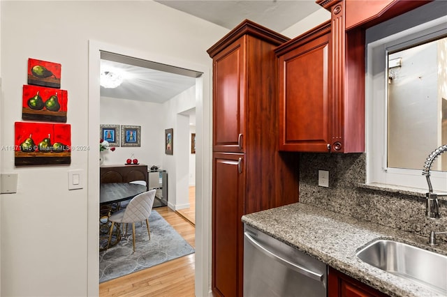 kitchen with decorative backsplash, light stone countertops, light hardwood / wood-style flooring, stainless steel dishwasher, and sink